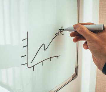 in einem Graph malt eine Person mit einem schwarzen Stift einen Pfeil nach oben zu einem Euro-Zeichen