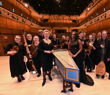 Ministerin Brandes steht mit den Musikerinnen und Musikern von Concerto Köln auf der Konzertbühne