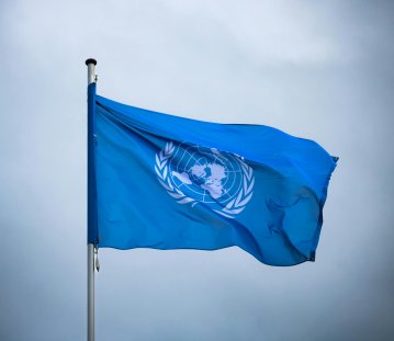 blaue Flagge der UN vor einem bewölkten Hintergrund
