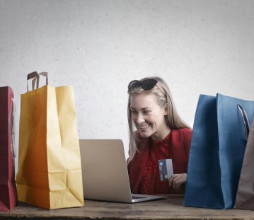 Frau beim Online-Shopping mit Einkaufstaschen