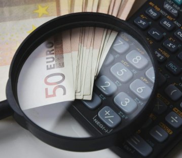 Geld und Taschenrechner liegen unter der Lupe