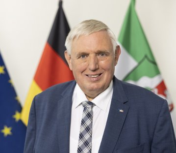 PHB Laumann, Karl-Josef - lächelnd, vor Flaggen (2022)