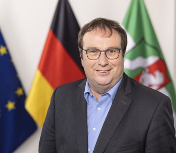 PHB Krischer, Oliver - lächelnd, vor Flaggen (2022)