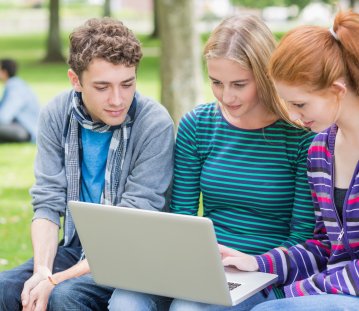 Schüler bzw. Jugendliche auf Parkbank vor Laptop 