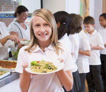 Kind in der Kantine mit Schulessen in der Hand