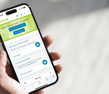 Eine Hand hält ein Handy, darauf zu sehen die „MeinELSTER+“-App