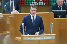 Ministerpräsident Hendrik Wüst steht am Rednerpult des Landtags Nordrhein-Westfalen und hält eine Rede