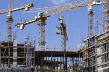 Auf dem Bild zu erkennen sind mehrere Baukräne auf einer Baustelle.