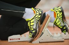 Füße in gelben Sportschuhen sind auf einem Startblock