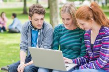 Schüler bzw. Jugendliche auf Parkbank vor Laptop 