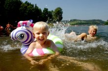 2 Kinder baden in einem See und lachen in die Kamera