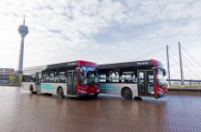 Zwei Busse stehen am Rheinufer mit dem Rheinturm und der Rheinkniebrücke im Hintergrund