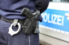 Polizist mit Waffe vor Polizeiwagen