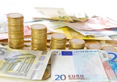 Auf dem Bild zu erkennen sind Euro-Geldscheine sowie aufgetürmte Euro-Münzen.