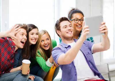 Das Foto zeigt mehrere lachende Jugendliche, die ein Selfie aufnehmen.