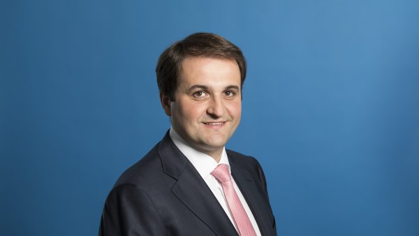 Chef der Staatskanzlei Nathanael Liminski freundlich lächelnd - Hintergrund blau.