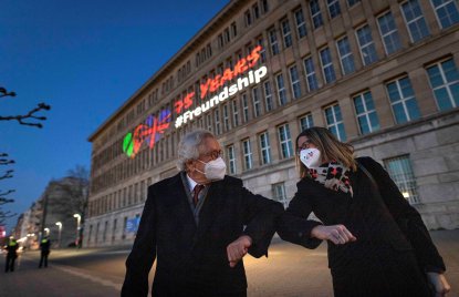 Der Minister und die Botschafterin begrüßen sich mit Corona-Gruß vor dem Behrensbau