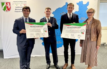 Minister der Finanzen Dr. Marcus Optendrenk, Netzwerkkoordinator Andre Niewöhner, Oberfinanzpräsident Reinhard Derix und LBF-Leiterin Stephanie Thien (v.l.) stehen vor einem Banner des Landeamtes zur Bekämpfung von Finanzkriminalität, in blau zu sehen eine Karte von NRW