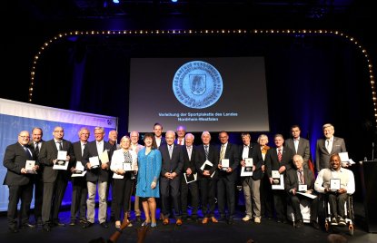 Gruppenfoto auf einer Bühne mit Staatssekretärin Milz und allen Trägern der Sportplakette.