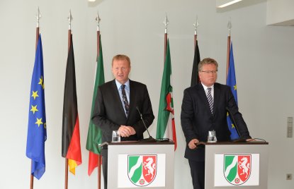 Innenminister Ralf Jäger und Regierungssprecher Thomas Breustedt stehen nebeneinander jeweils hinter einem Stehpult