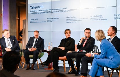 Ein spricht auf einem podium, neben ihm Ministerin Neubaur