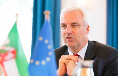 Minister Duin vor einer NRW und einer EU-Tischflagge