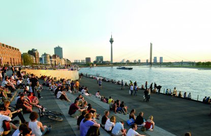 Sitzende Menschen auf Treppe am Rhein