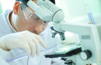 Das Foto zeigt einen Forscher an einem Mikroskop.