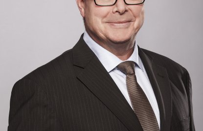 Frank Hoever lächelnd vor grauem Hintergrund