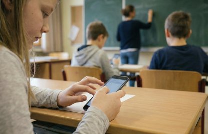 Schüler:innen sitzen im Klassenzimmer und spielen am Handy