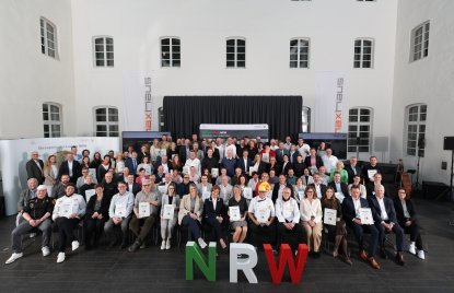 alle Preisträger der Meister.Werk.NRW Auszeichnung 2025 sitzend und stehend mit Urkunden in den Händen vor dem Maxhaus, in der Mitte vorne Ministerin Gorißen