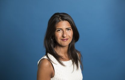 Staatssekretärin Serap Güler freundlich lächelnd - Hintergrund blau.