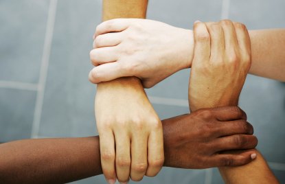 Nahaufnahme von 4 Menschen, die sich am Handgelenk anfassen