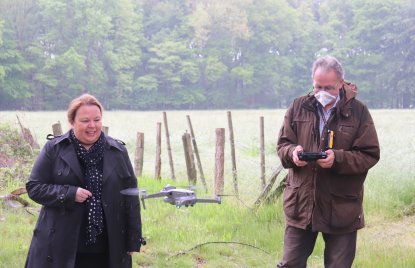Ministerin Heinen-Esser steht in einer Wald-Lichtung vor einer fliegenden Drohne