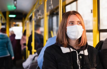 Eine junge Frau trägt eine Mund-Nasen-Schutz-Maske im Bus