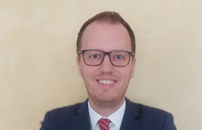 Jens Seidler, neuer Leiter der JVA Bielefeld-Senne, im dunkelblauen Anzug und roter Krawatte vor hellem Hintergrund.