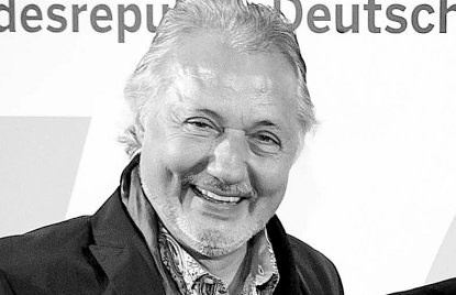 Konrad Beikircher vor einer Fotowand auf einer Preisverleihung