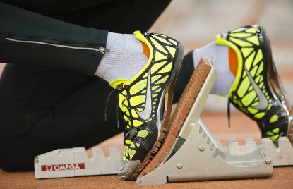 Füße in gelben Sportschuhen sind auf einem Startblock
