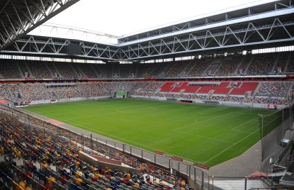 Fußballstadion mit offenen Dach kurz vor einem Spiel, die Tribünen sind größtenteils gefüllt.