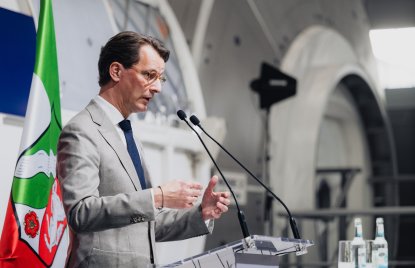 MP Wüst während seiner Rede vor einer Raumfahrtkapsel