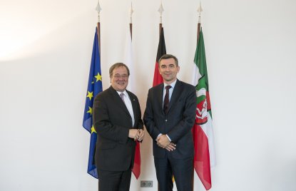 Ministerpräsident Armin Laschet und der polnische Botschafter Andrzej Przyłębski, im Hintergurnd 4 verschiedene Flaggen.