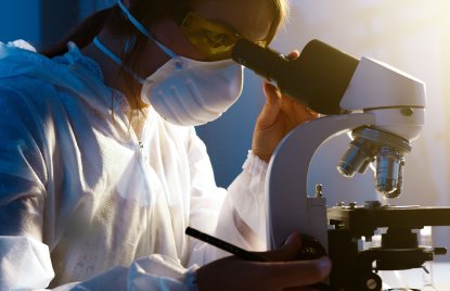 Eine Wissenschaftlerin benutzt ein Mikroskop in einem Labor und konzentriert sich intensiv auf ihre Forschung.
