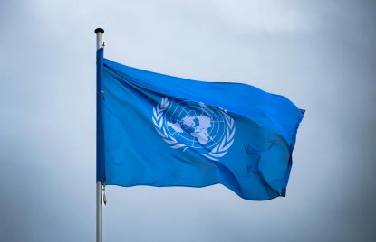blaue Flagge der UN vor einem bewölkten Hintergrund