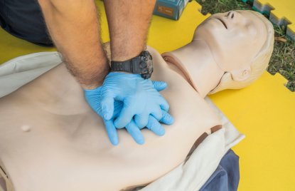 Nahaufnahme von Händen, die Hilfeleistung an einer Puppe für Erste-Hilfe-Training durchführen