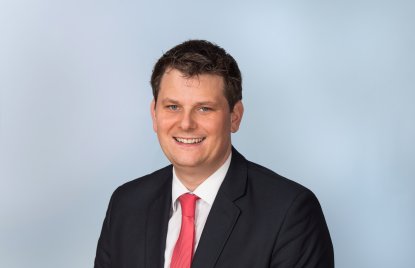 Polonia-Landesbeauftragter Thorsten Klute lächelnd im schwarzen Anzug, weißem Hemd und roter Krawatte.