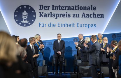 Mario Draghi steht auf der Bühne während das Publikum applaudiert