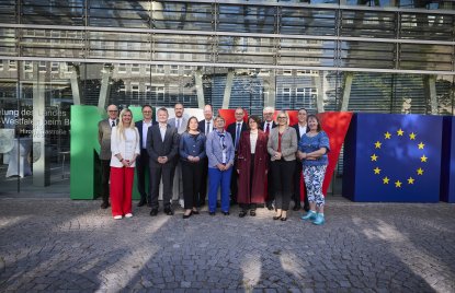 Eine Gruppe menschen steht vor riesigen Buchstaben N R und W und einem Würfel mit dem Europa-Logo