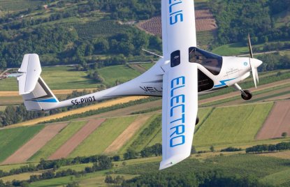 Ein weißes Flugzeug fliegt hoch über einigen Feldern