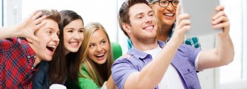 Das Foto zeigt mehrere lachende Jugendliche, die ein Selfie aufnehmen.